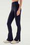 A person wearing the SPLITS59 Raquel High Waist Flare w/ Split Hem - Black leggings and white sneakers stands against a plain background.