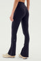 A person showcasing a sleek silhouette in the Raquel High Waist Flare w/ Split Hem leggings in black by SPLITS59, paired with beige sneakers and facing away from the camera.