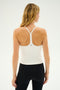 A woman with long blonde hair is seen from the back, wearing the SPLITS59 Airweight Tank in white and black leggings against a white background.
