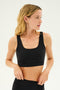 A woman with long blonde hair wears a black Sprint Rigor Bra by SPLITS59 and looks to the side against a plain background.