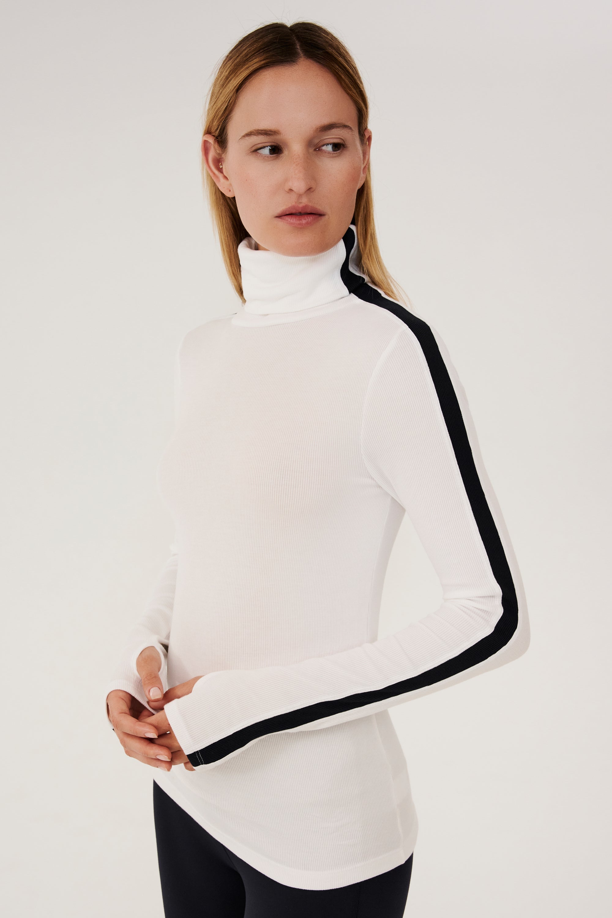 A woman wearing a SPLITS59 Jackson Rib Full Length Turtleneck in White and Black leggings.