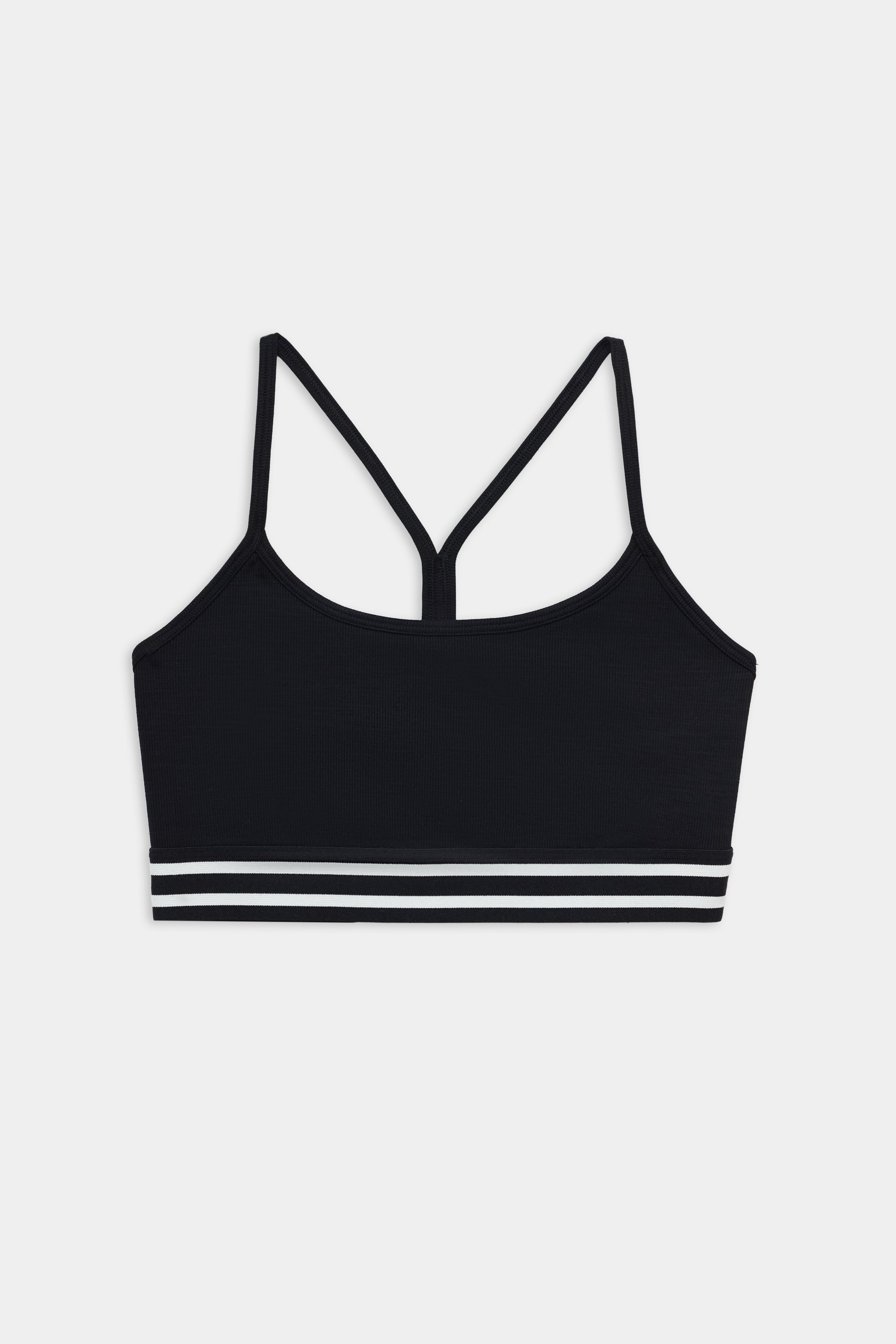 The SPLITS59 Cali Active Rib Bra in black features thin shoulder straps and two white stripes on the elastic band, showcased against a plain white background.