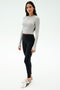 A person stands facing forward wearing the SPLITS59 Louise Rib Long Sleeve Crop in Heather Grey, paired with black leggings and white sneakers, against a plain white background.