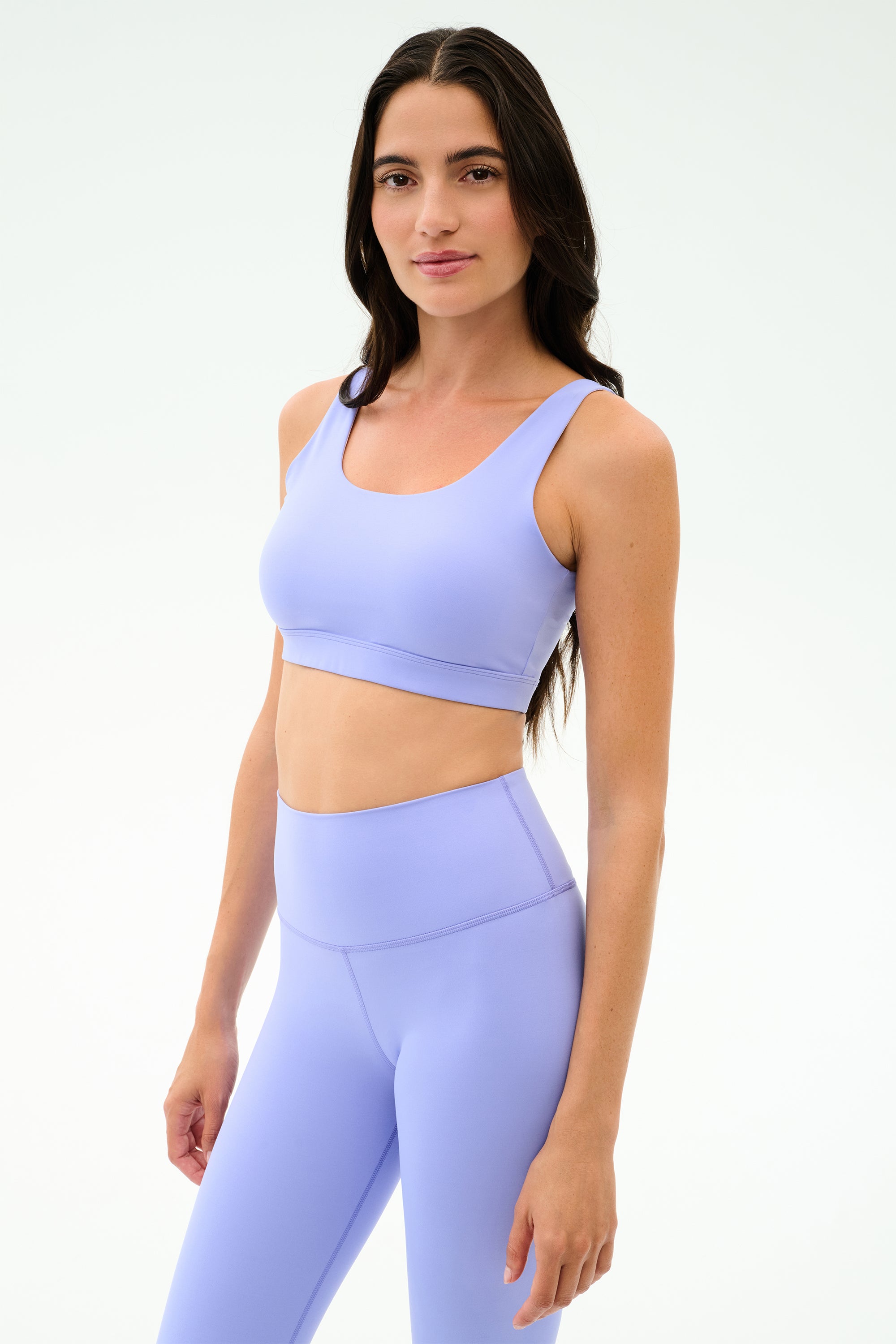 A woman wears the SPLITS59 Sprint Rigor Bra in Purple Haze with matching high-waisted leggings, ideal for gym workouts or multi-sport performance, against a plain white background.