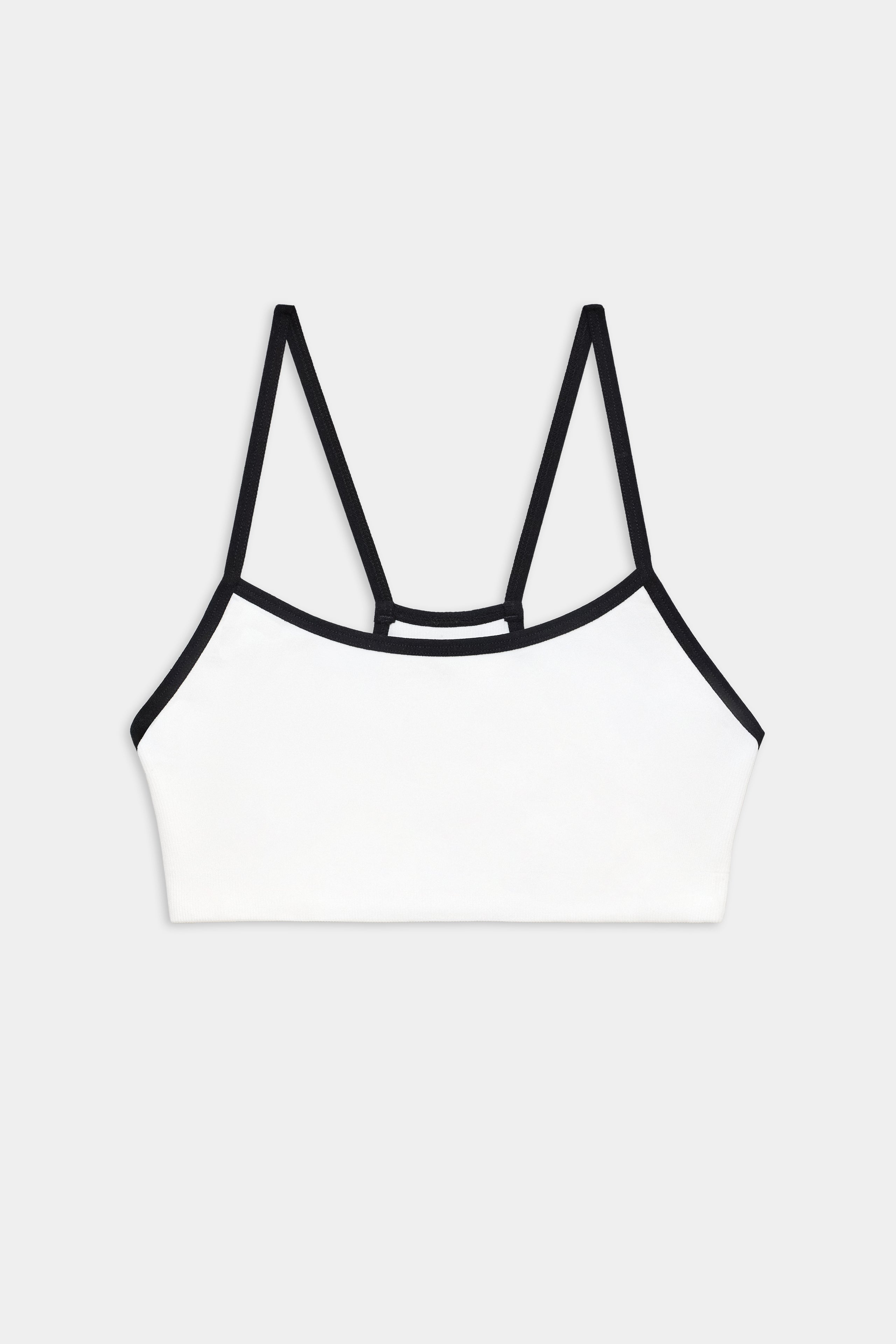 White bralette with thin black straps and black trim, displayed on a plain light gray background.