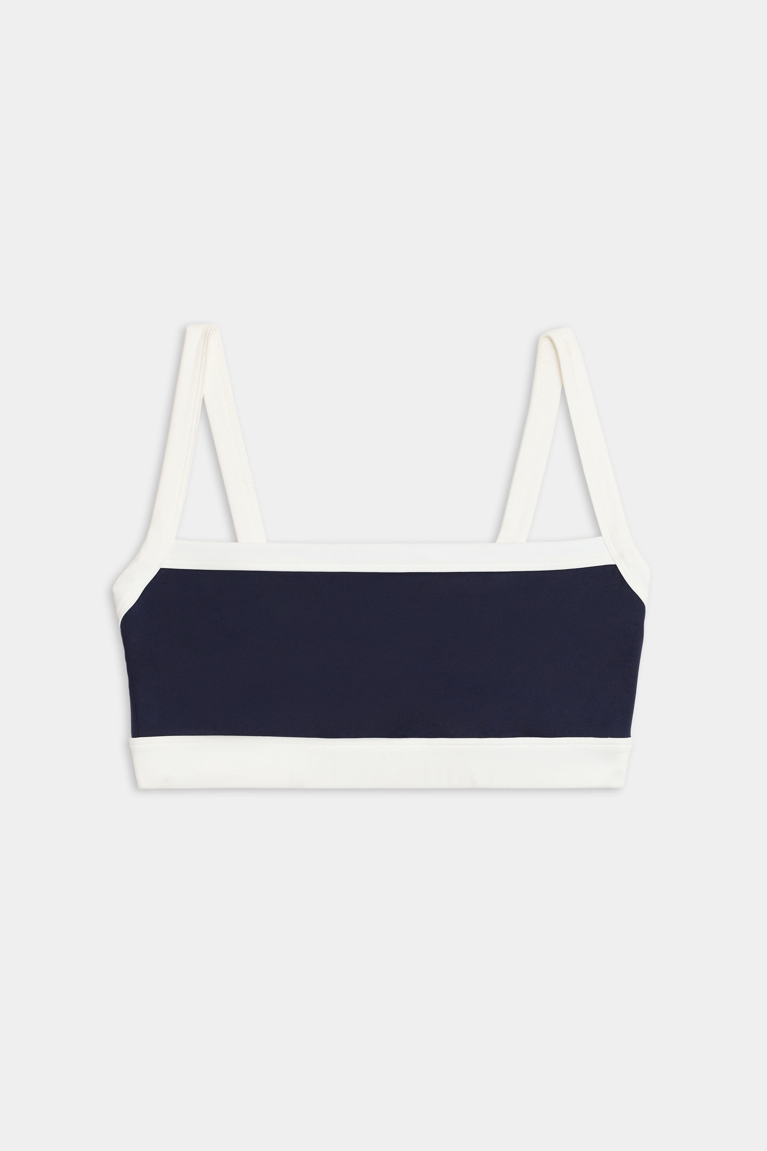 The SPLITS59 Monah Rigor Bra is a navy blue and white color block bralette with thin white straps, shown laid flat on a plain background.