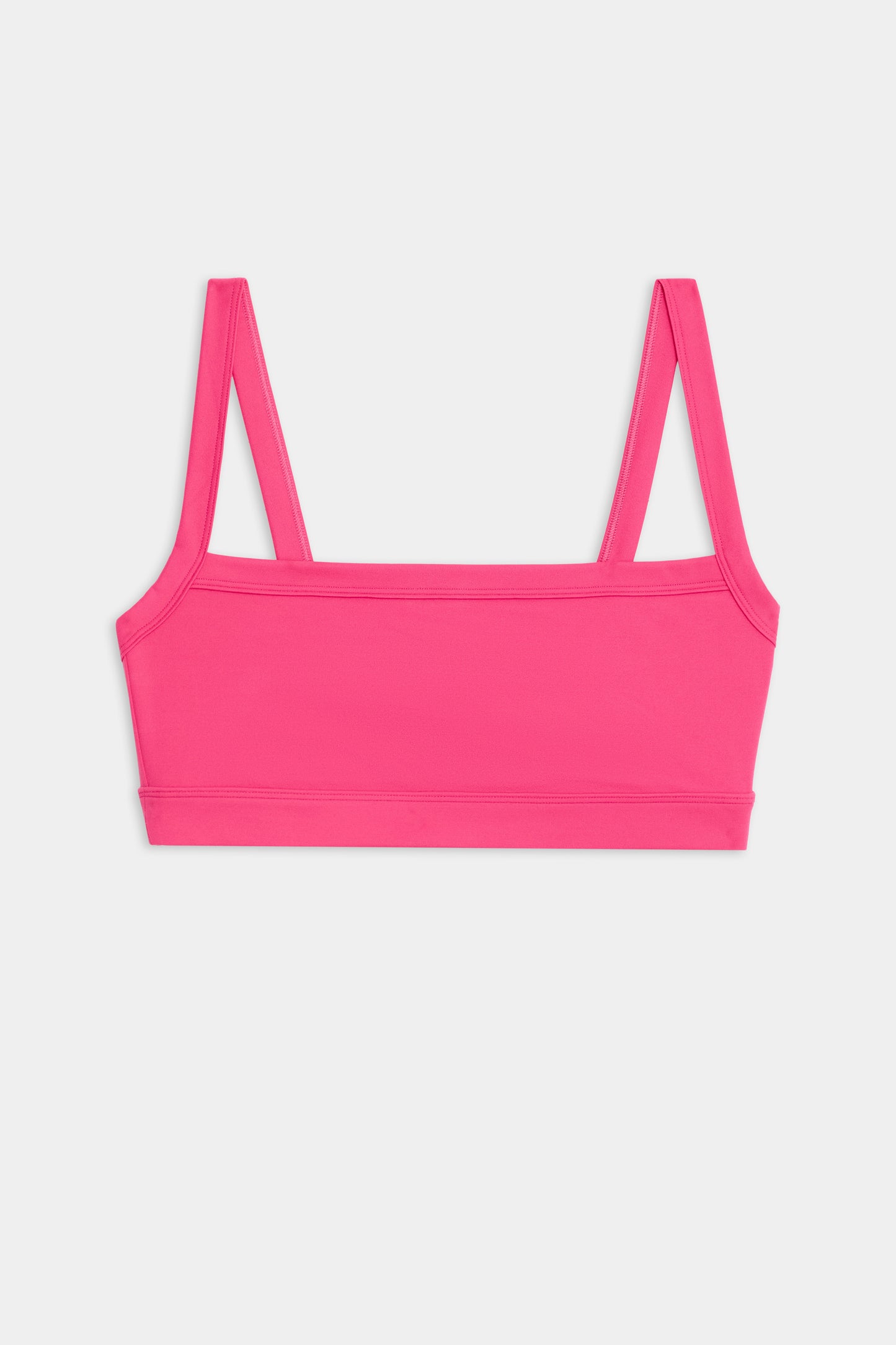 The Monah Rigor Bra by SPLITS59 features a pink design with double straps and a square neckline, set against a white background.