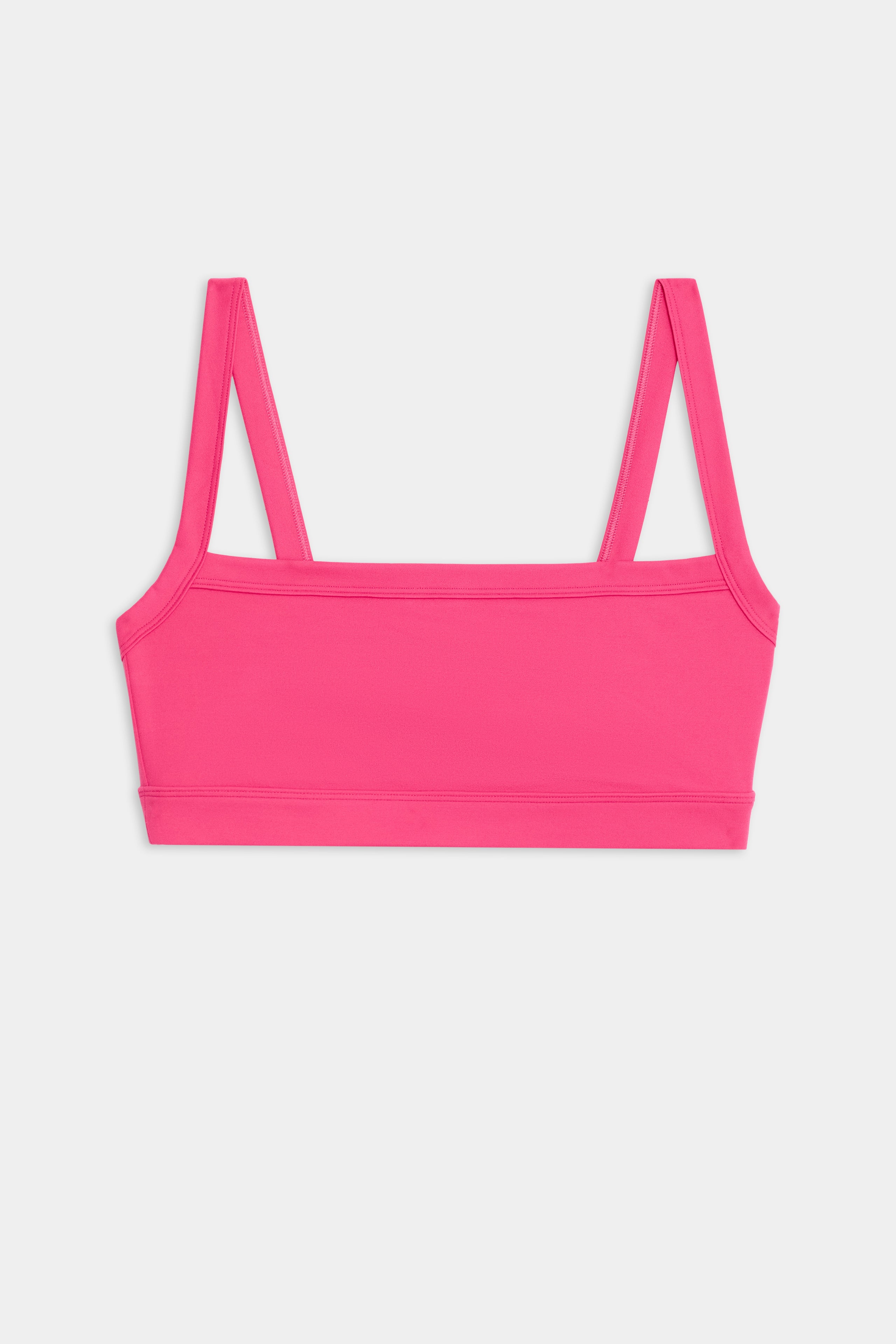 The Monah Rigor Bra by SPLITS59 features a pink design with double straps and a square neckline, set against a white background.