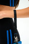 Close-up of a person in a black outfit with blue stripes, holding the SPLITS59 MZW x Splits59 Metro Key Pouch Wristlet by its strap.