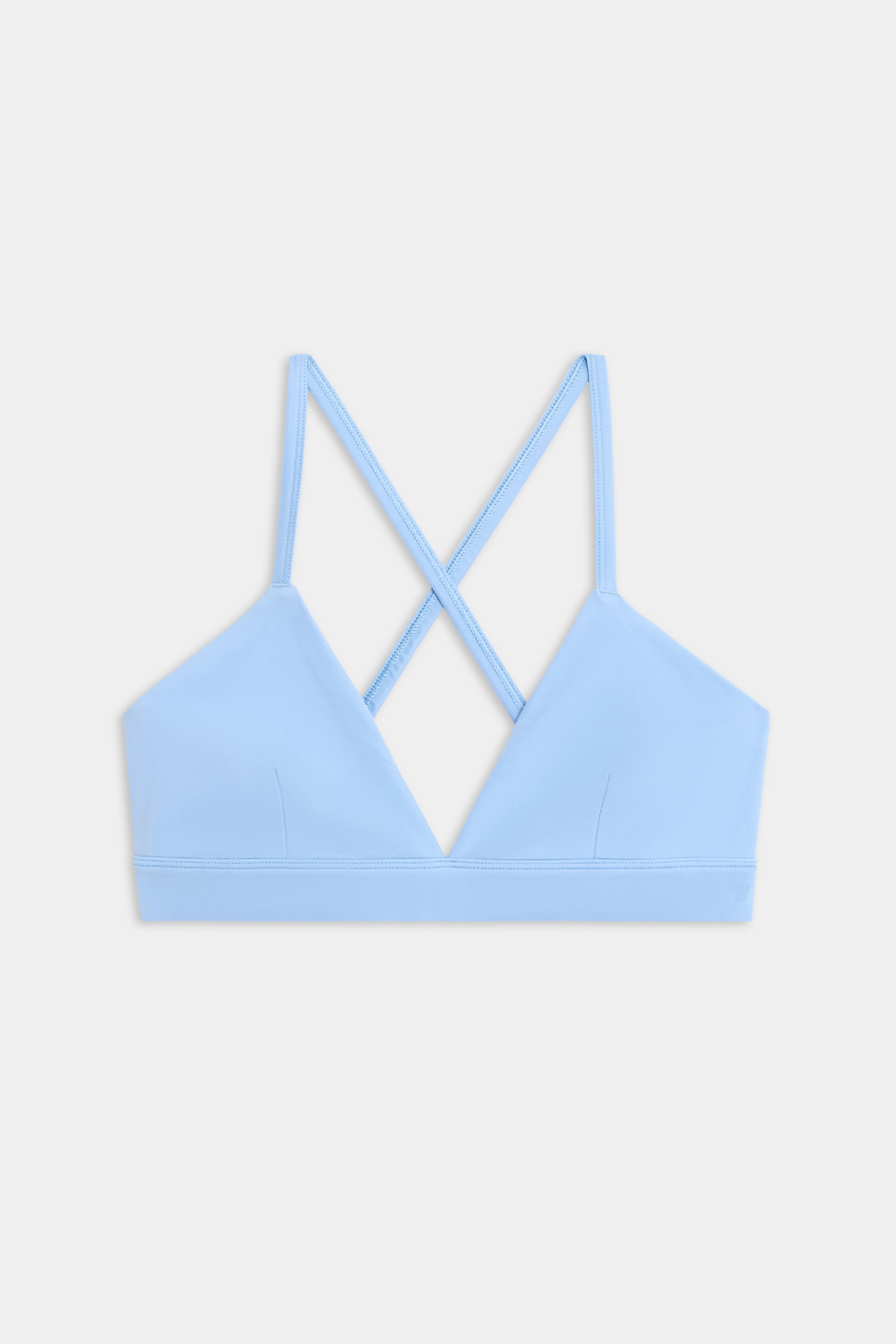 The SPLITS59 Theo Rigor Bra features a light blue shade with thin straps and a crisscross back design, showcased against a plain white background.