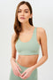 Front view of girl wearing light green sports bra with two thin white stripes down the side and light green leggings 