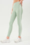 Side view of girl wearing light green leggings with two thin white stripes down the side with white shoes