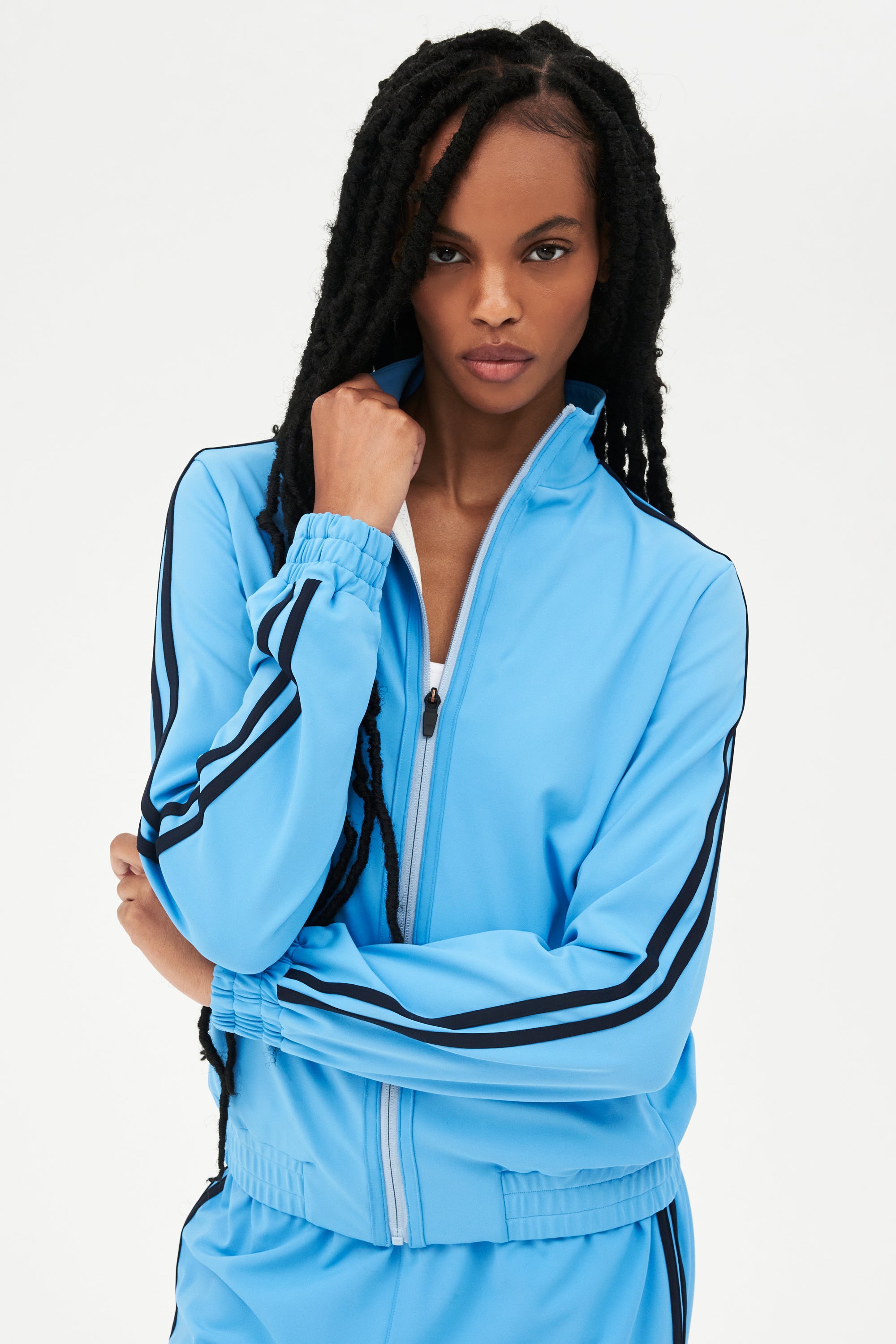 A woman wearing a SPLITS59 Fox Techflex Jacket in Cloudy Sky/Indigo, with black stripes, radiating a retro vibe.