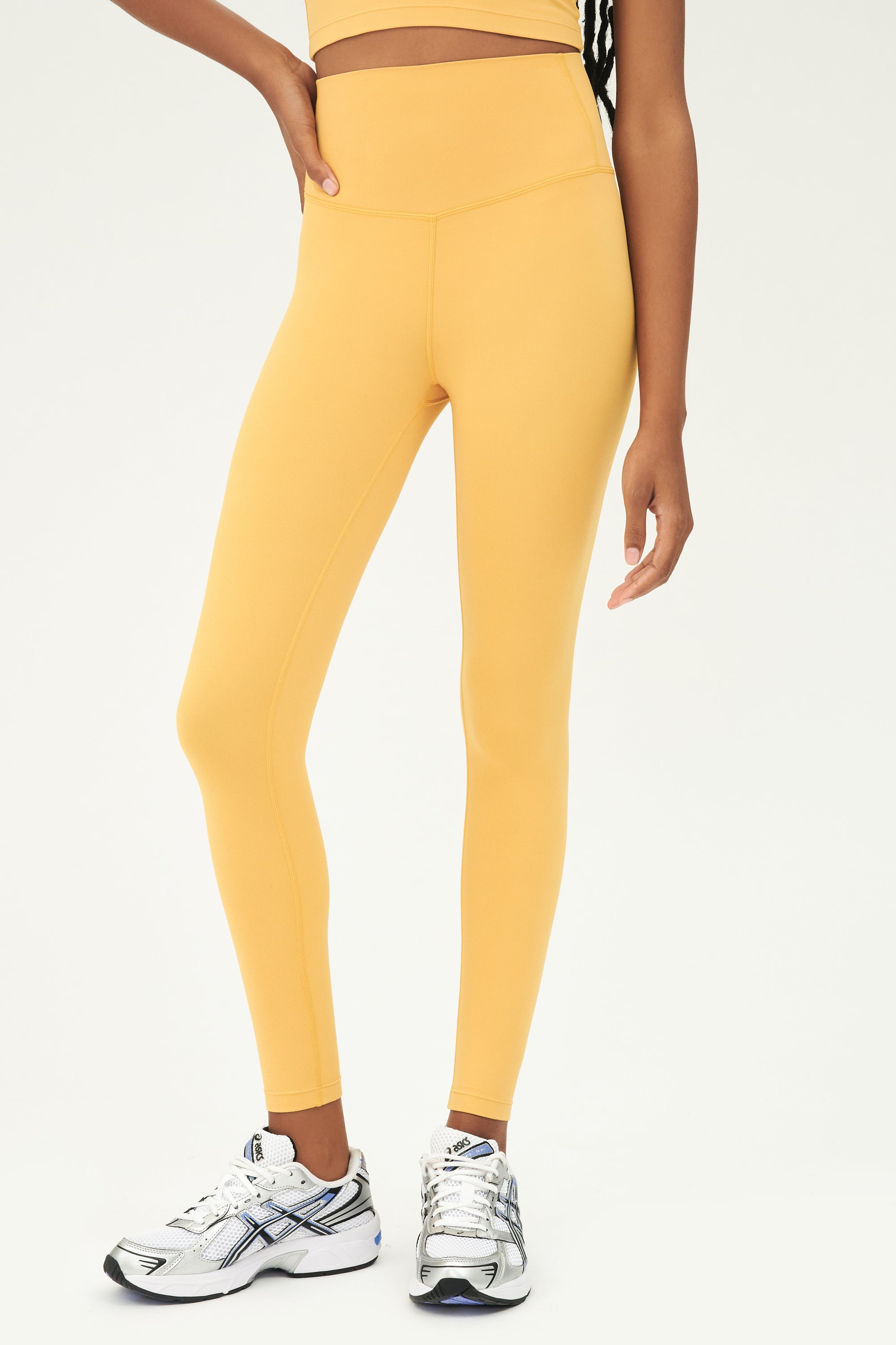 Front view of girl wearing highwasited yellow leggings and white shoes