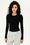 A woman wearing a SPLITS59 Loren Seamless L/S Tee in Black and grey sweatpants for yoga.