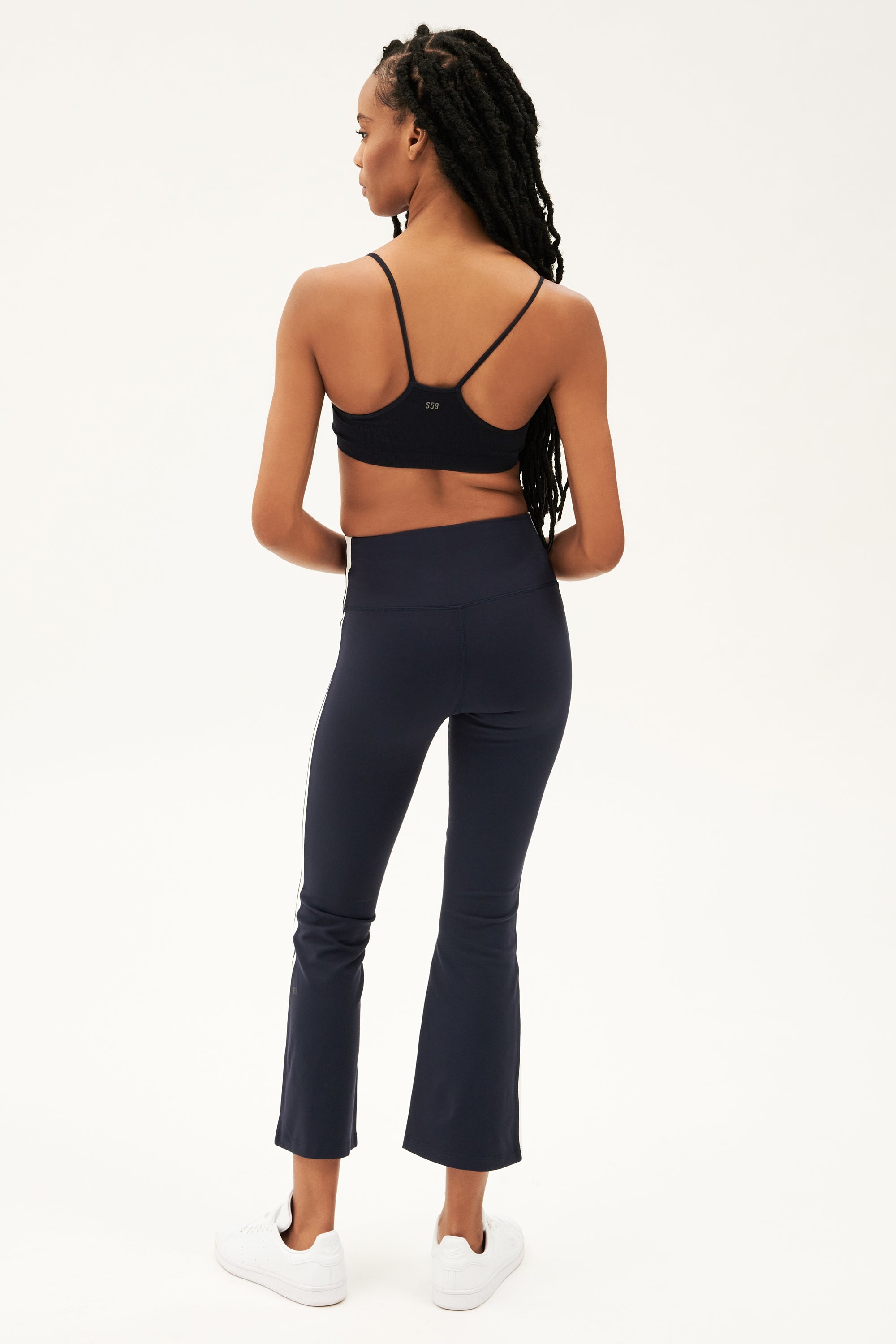 The back view of a woman wearing SPLITS59 Raquel High Waist Crop - Indigo/White top and 4-way stretch supplex fabric leggings.