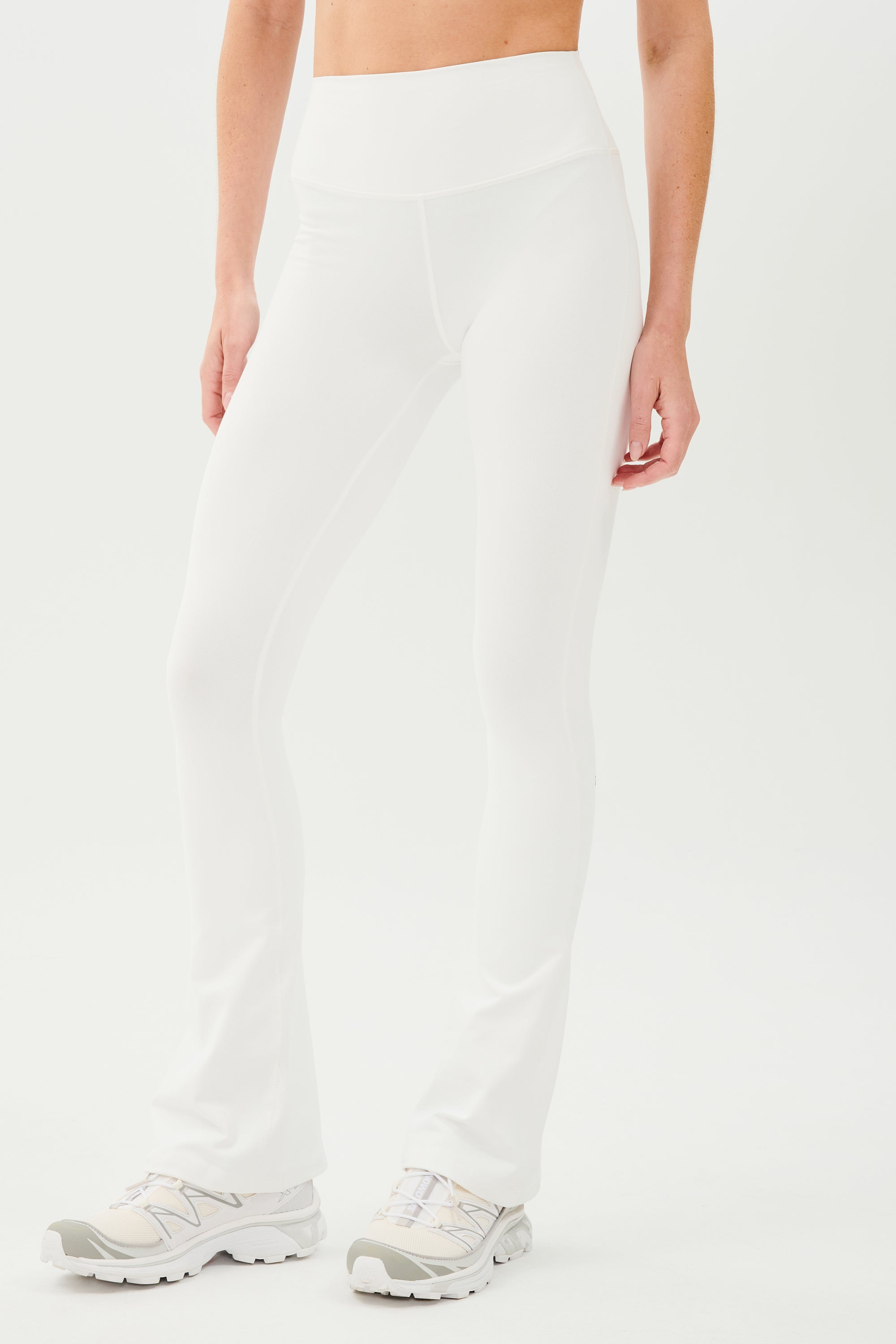 A woman wearing SPLITS59 Raquel High Waist Flared Legging in White and a tank top.
