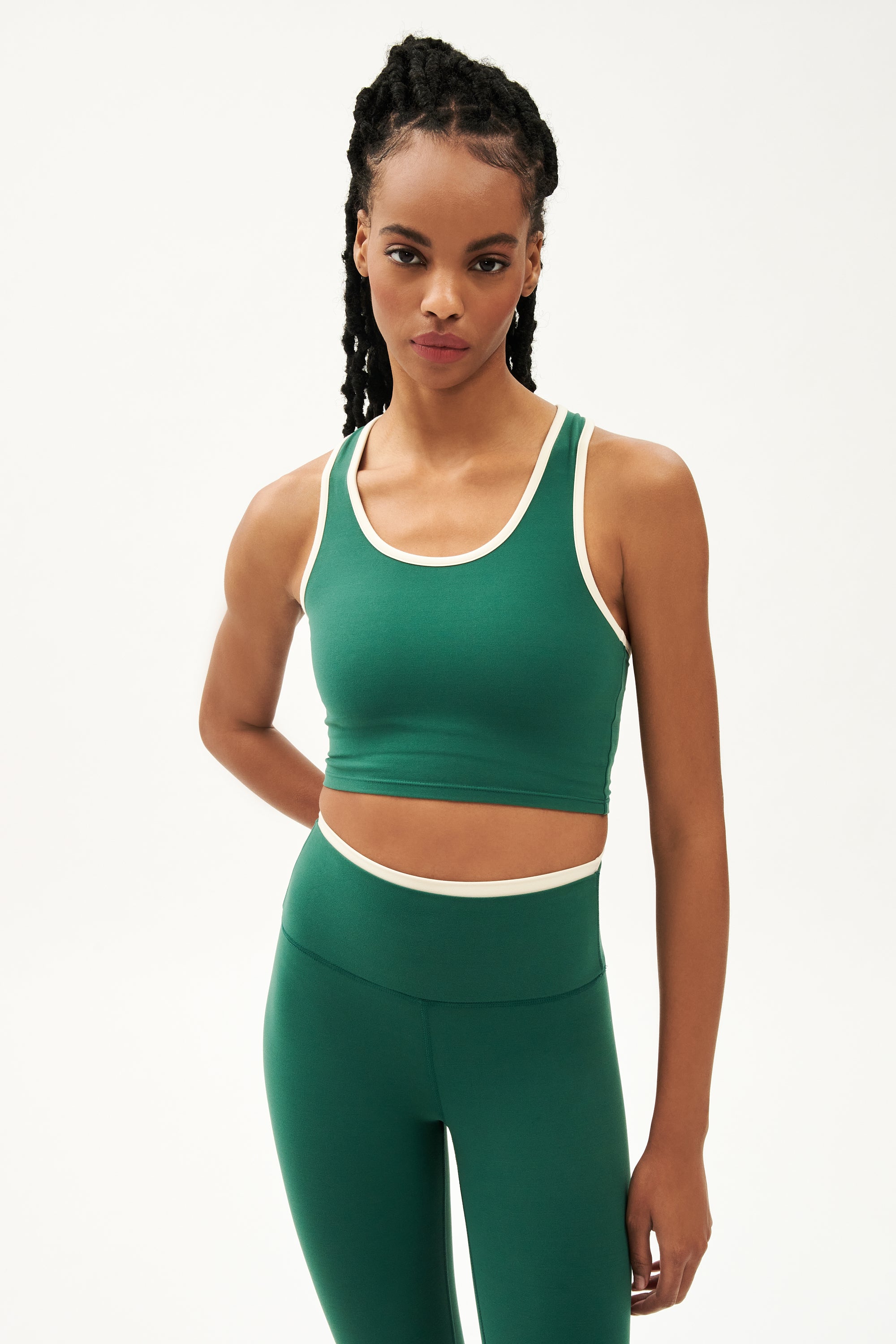 Front view of girl wearing cropped green tank top with white trim and green leggings with a thin white waistband