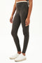 Side view of girl wearing dark grey leggings with thin white band around waist with white shoes