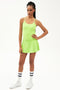 Full front view of girl wearing neon green upper thigh skirt with built in shorts, neon green  tank top and white shoes