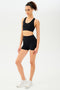 Full side view of girl wearing black shorts with black sports bra and white shoes