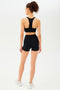 Full back view of girl wearing black shorts with black sports bra and white shoes