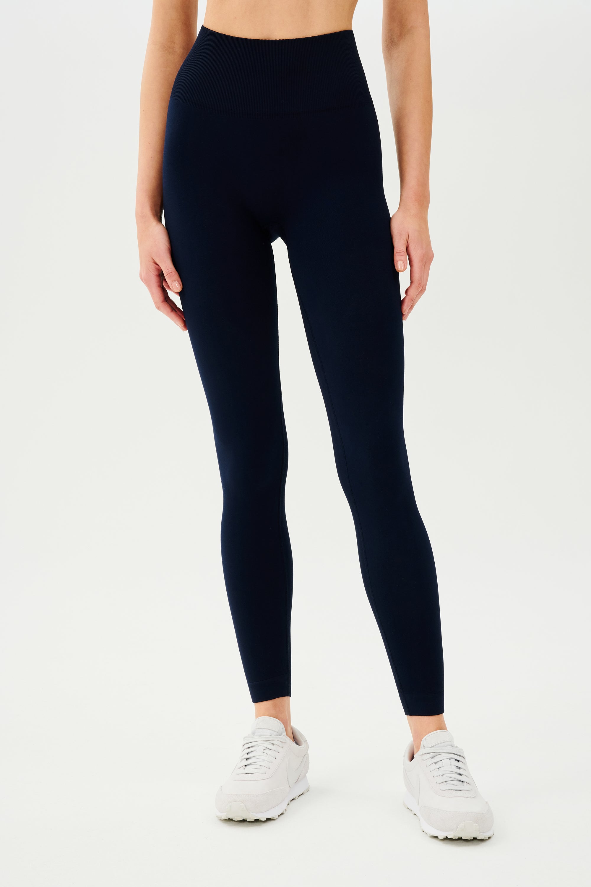 The back view of a woman wearing SPLITS59 Loren Seamless High Waist Full Length leggings in Indigo.